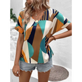 A woman wears a vibrant geometric-patterned women’s clothing printed v-neck top in teal orange navy blue and cream