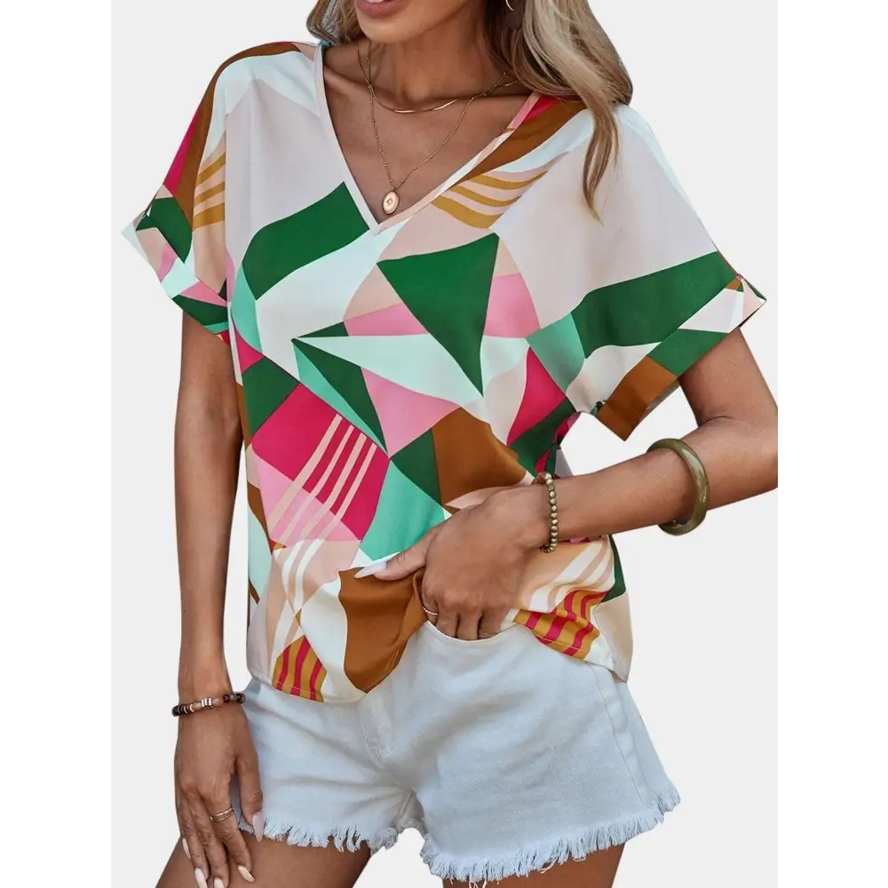 A vibrant geometric-patterned women’s clothing printed v-neck top in shades of green pink brown and white