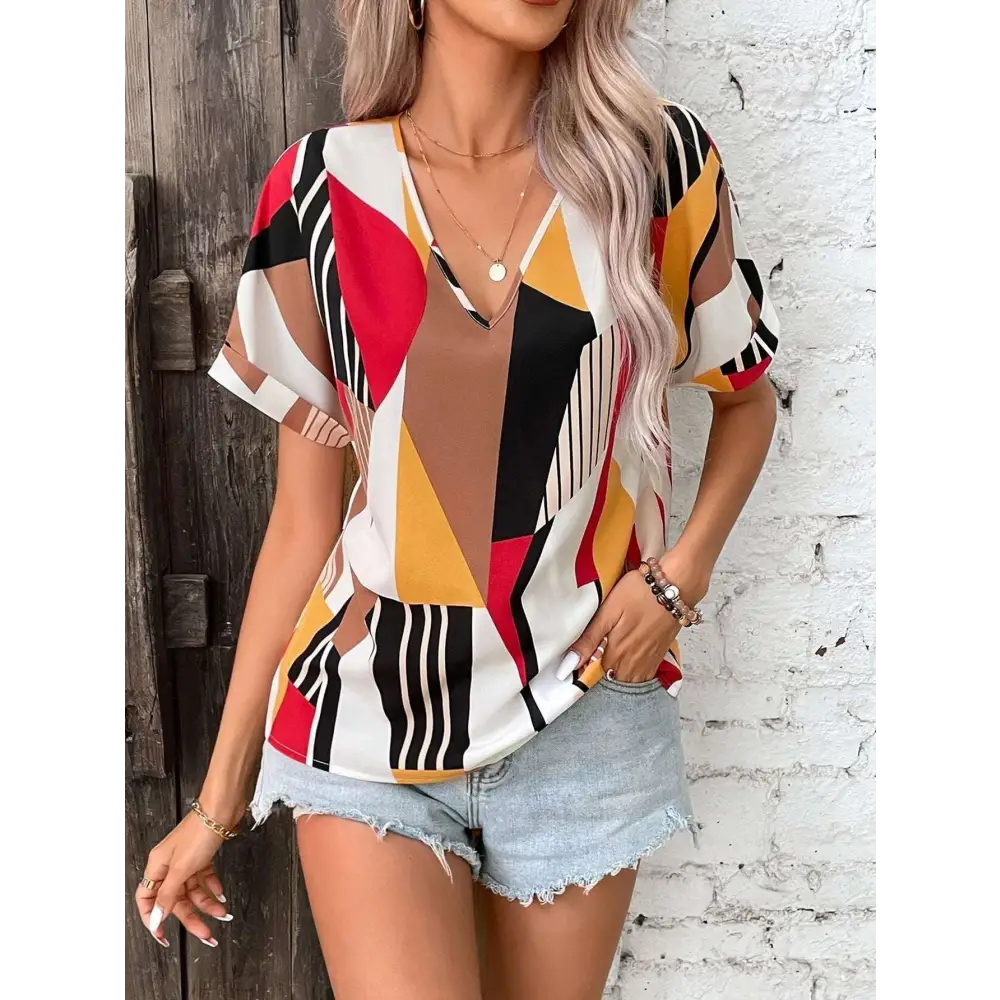 A vibrant geometric-patterned women’s short-sleeve top with a v-neckline in red black yellow and white perfect for casual wear