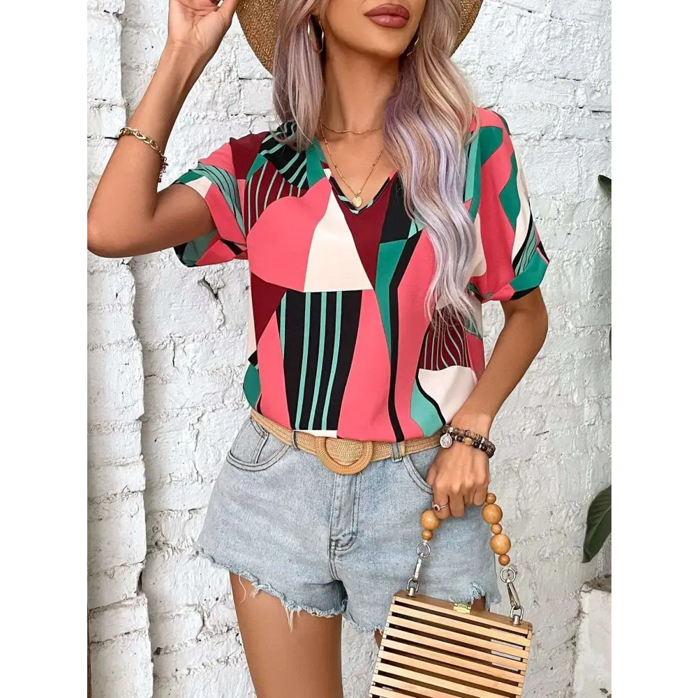A vibrant geometric-patterned women’s short-sleeve top in pink green black and white with a v-neckline for casual wear