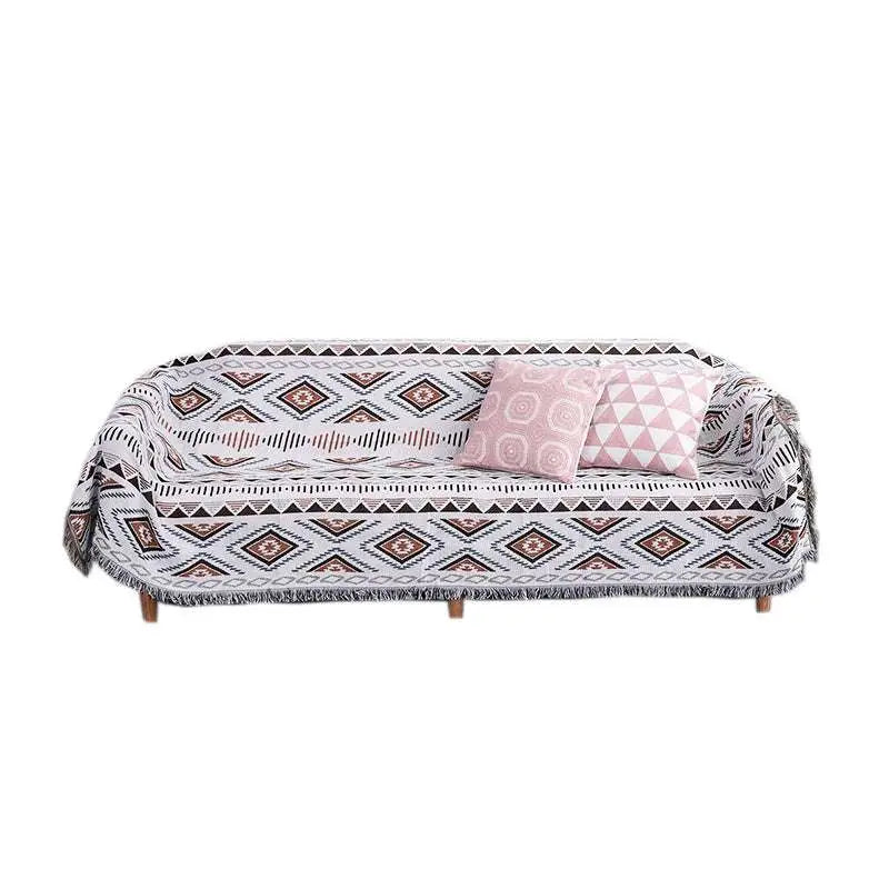 Geometric woven fringed sofa blanket in white with black and dusty rose diamond patterns and a fringed edge