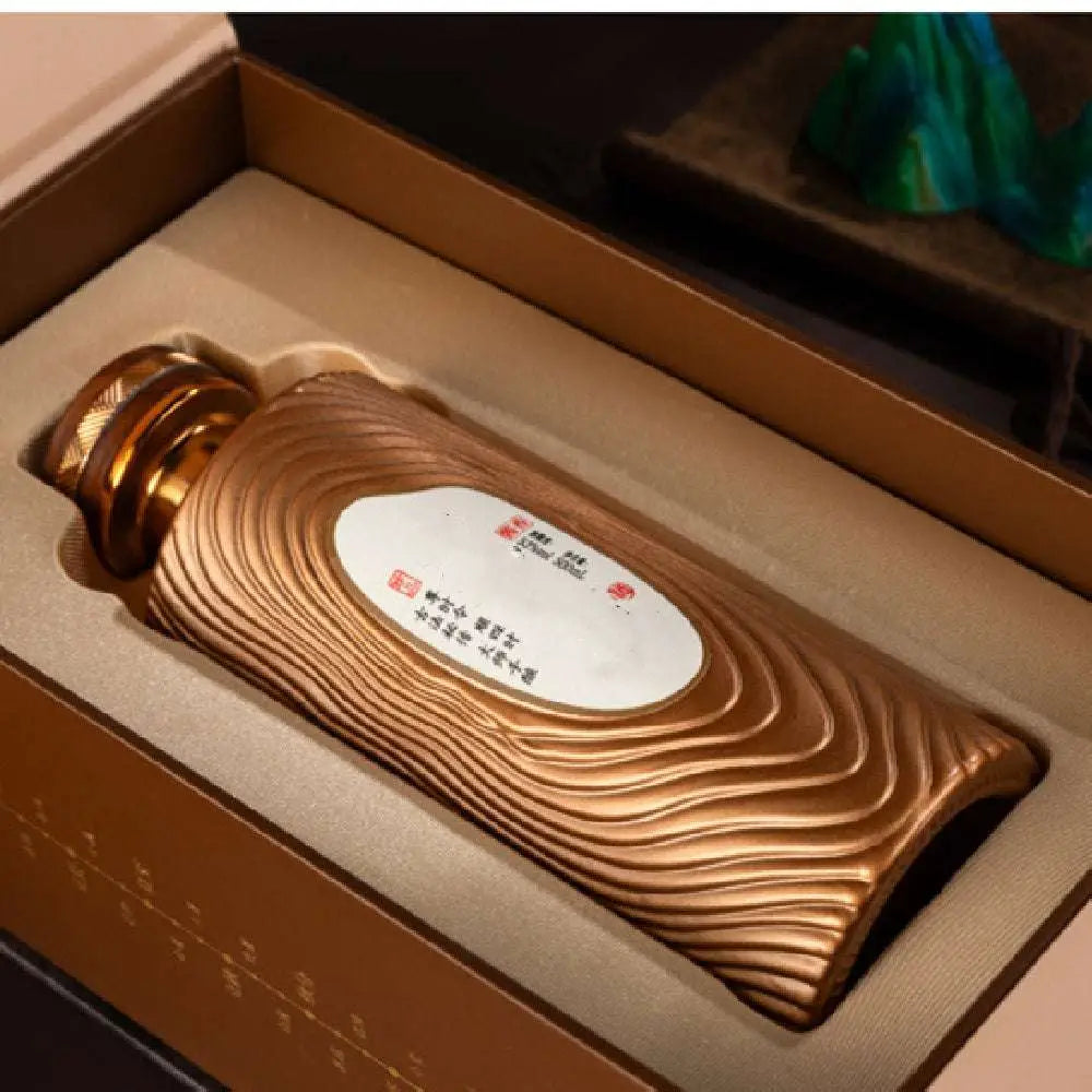 Golden wave-patterned ceramic wood grain bottle with matching cap and white label in gilded liquor gift box set
