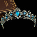 An ornate silver crystal bridal crown with large blue teardrop crystals and gold baroque rhinestone accents