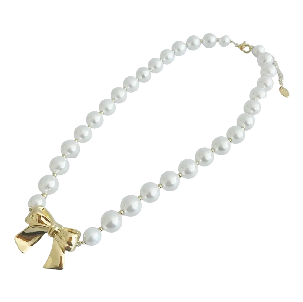 A pearls necklace with lustrous white pearls and a gold bow pendant perfect for luxury women’s fashion