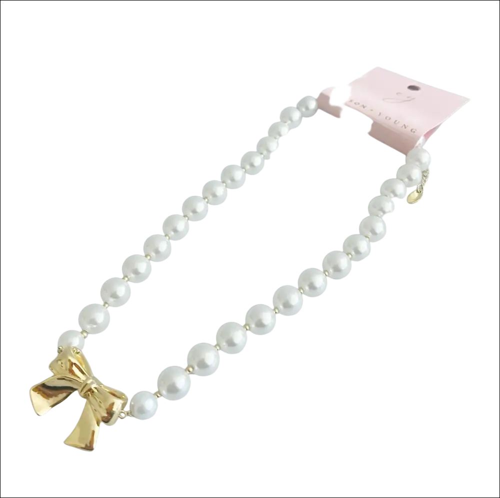 A delicate white pearls necklace with a shiny gold bow pendant ideal for luxury women’s fashion