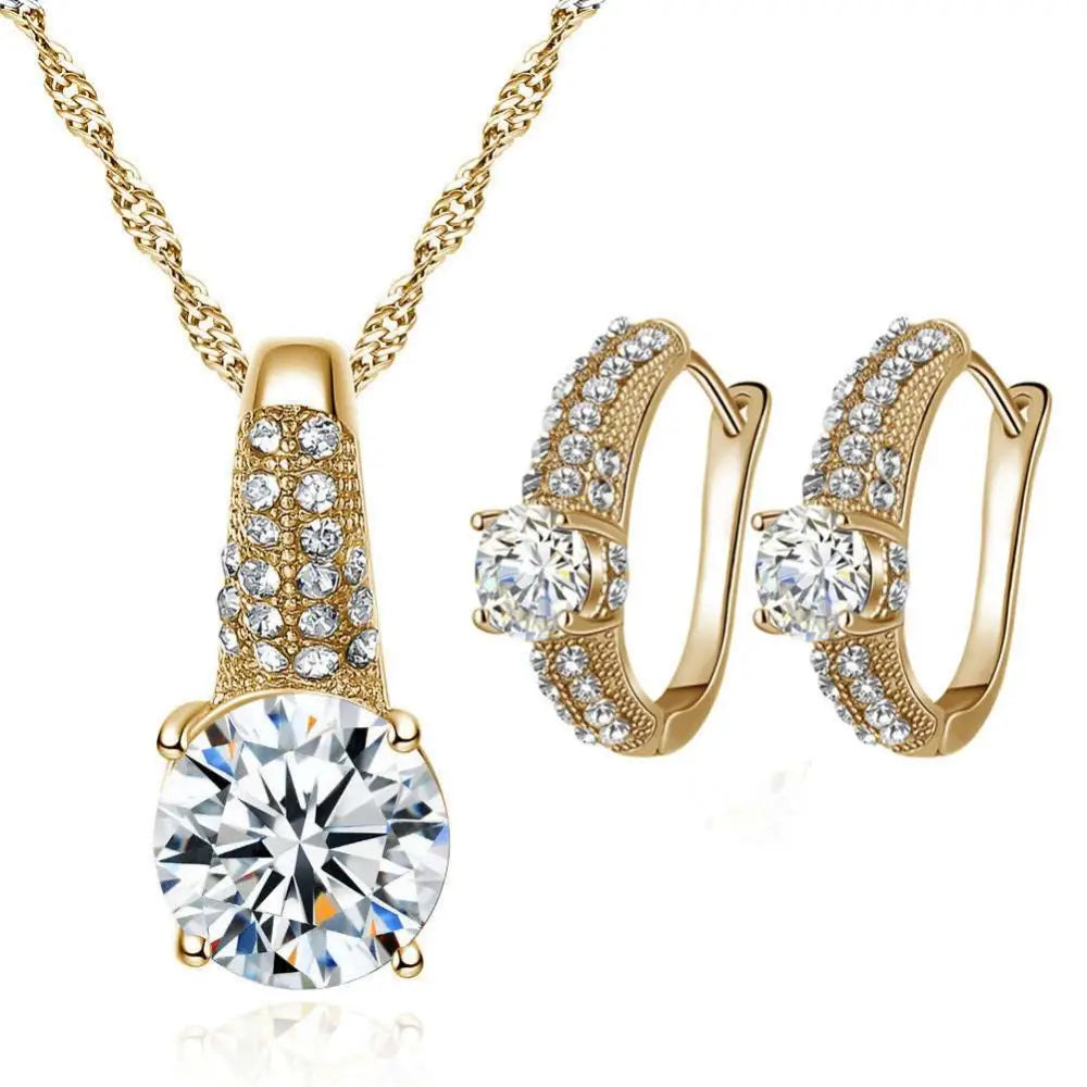 Gold bridal necklace and earrings jewelry set featuring a gold-toned pendant with round-cut clear gemstone and matching hoops