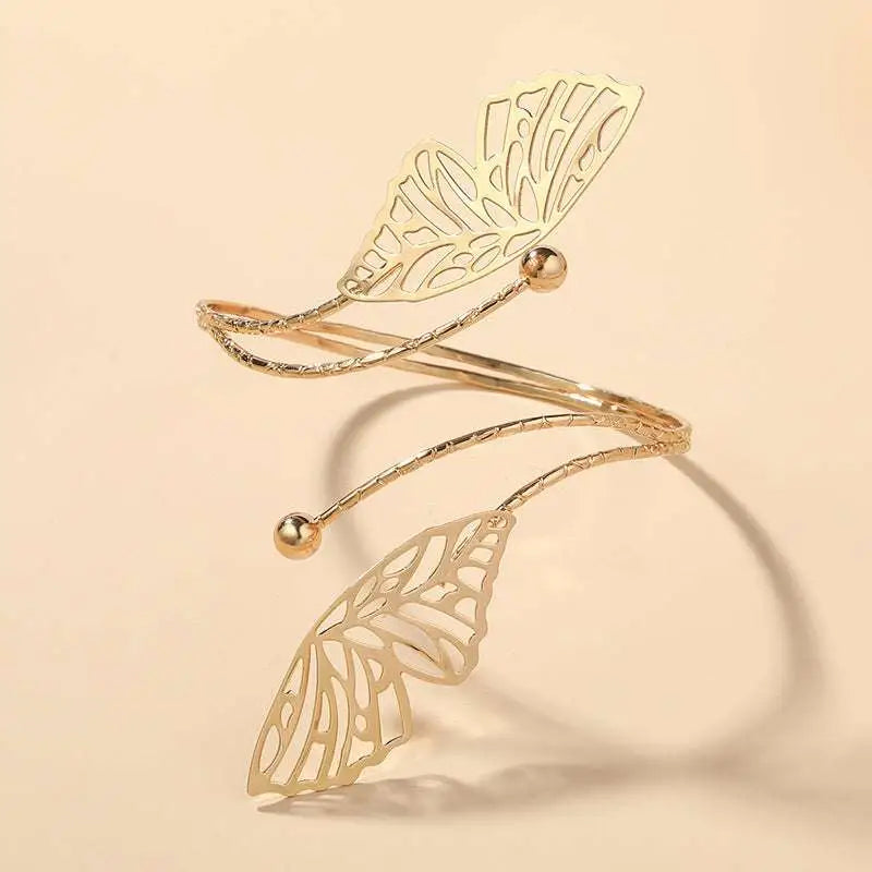 Gold butterfly arm cuff with intricate cut-out gold-toned butterfly wing design and small spherical accents
