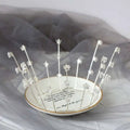 Silver star-adorned handmade star crown resting on white ceramic dish with gold rim for gold crystal bride wedding jewelry