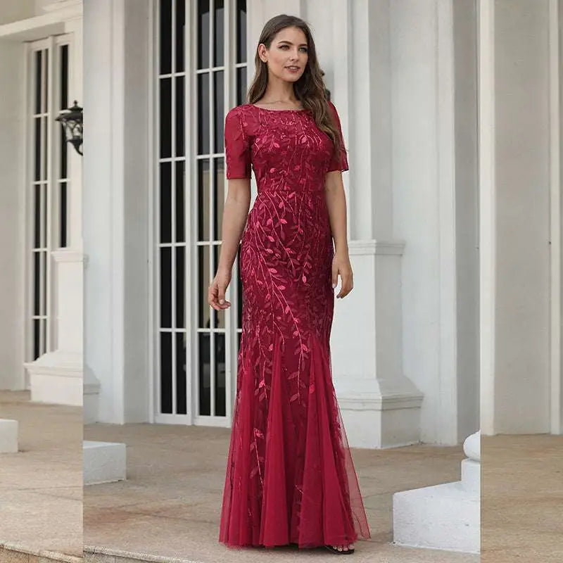 A deep red temperament mermaid dress featuring intricate lace and gold embellishments with a fitted silhouette