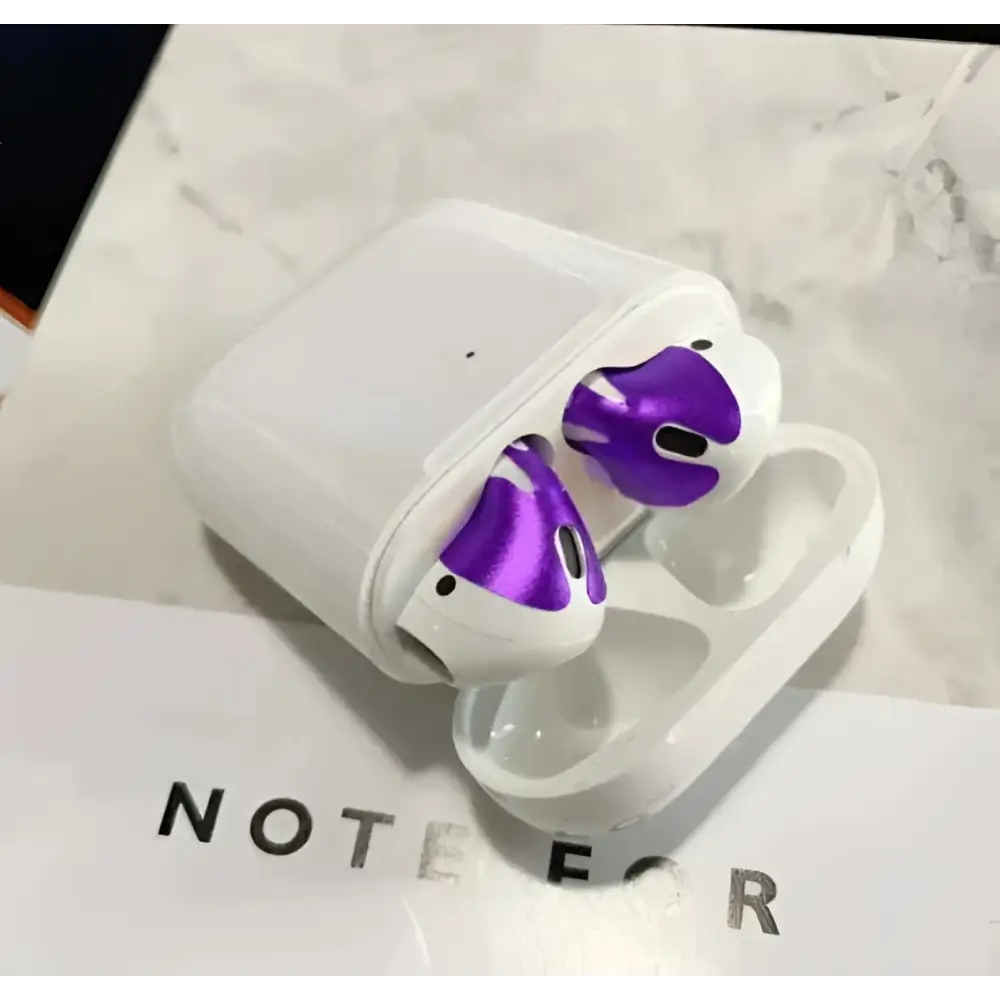 White apple airpods with purple metallic accents featuring a gold glossy custom sticker skin and matching charging case