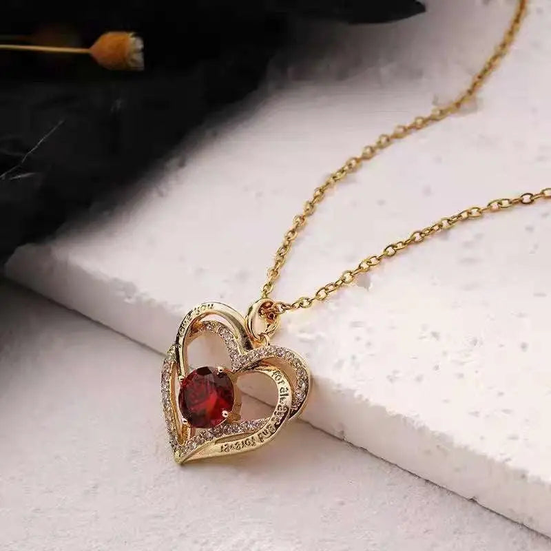 Gold heart red sapphire pendant necklace with central red gemstone surrounded by diamonds engraved with i love you