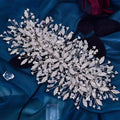 A sparkling silver luxurious exaggerated crystal leaf bridal headpiece with intricate branching designs and dangling beads