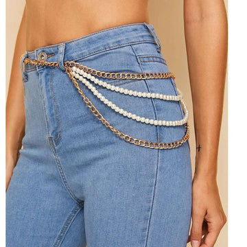 Gold-toned waist chain with three rows of white pearls draped over blue denim jeans as gold pearl jewelry accessory