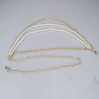 Gold-toned waist chain with three parallel strands featuring two pearl jewelry accessories and one plain metal chain