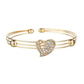 Gold-toned bangle bracelet with a central heart-shaped charm adorned with clear crystals in a gold rhinestone heart love jewelry set