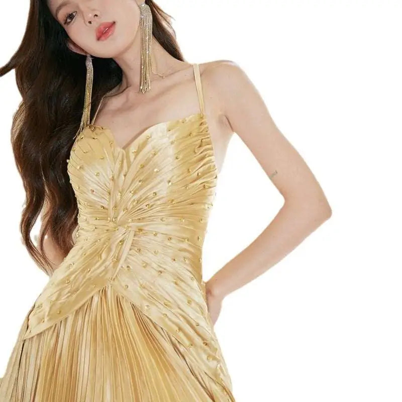 A shimmering gold satin heavy industry birthday dress with ruched bodice pleated skirt and sparkling embellishments
