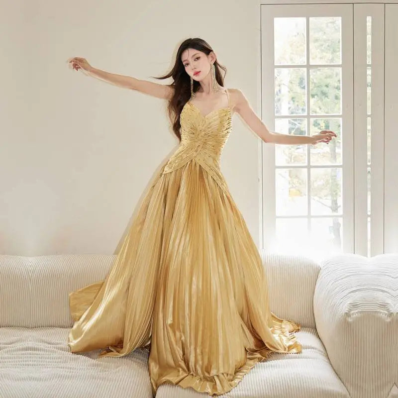 A shimmering gold satin heavy industry birthday dress with a fitted bodice and flowing pleated skirt
