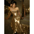 A gold sequined off-shoulder dress bridal fishtail with draped cap sleeves and a fitted bodice for formal events