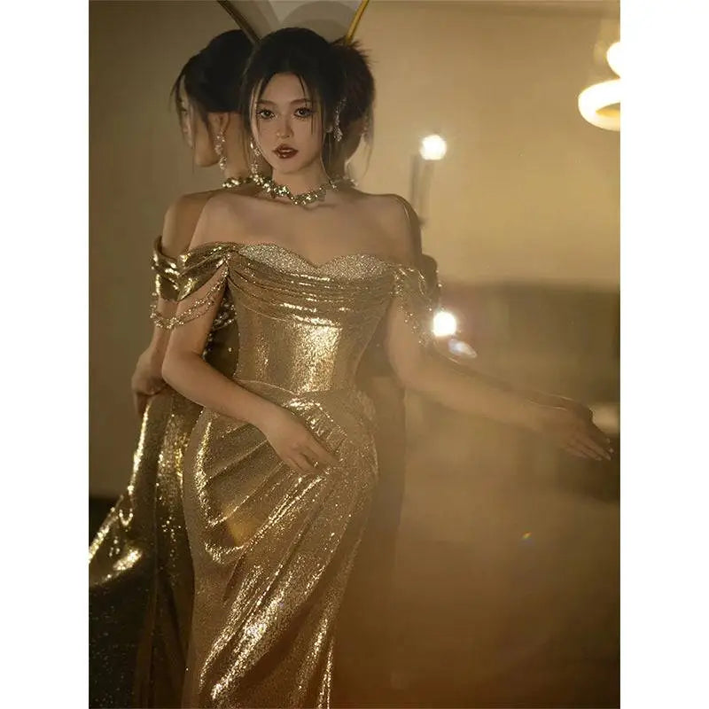 A gold sequined off-shoulder dress bridal fishtail gown with a fitted bodice and flowing skirt perfect as a toast dress bridal