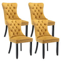 Set of four gold tufted velvet dining chairs with mustard-yellow upholstery black legs and nailhead trim