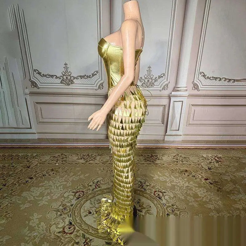 A shimmering gold metallic mermaid gown with fitted bodice and cascading triangular scales features a golden bright surface bandage design