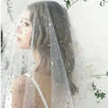 A delicate white sheer fabric golden shiny big veil adorned with scattered star-shaped embellishments in gold and silver
