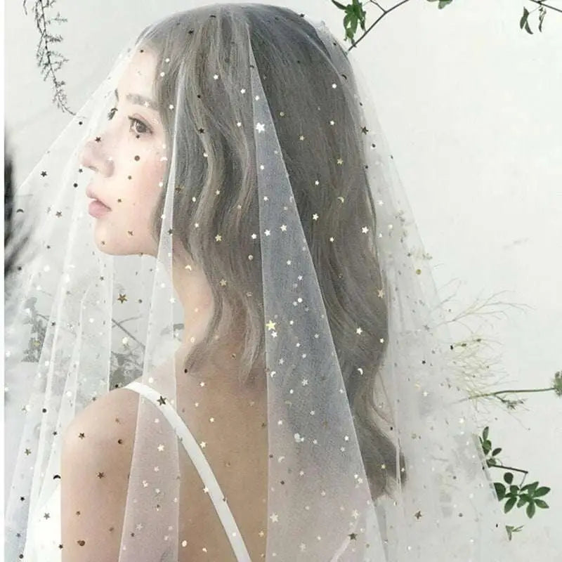 A delicate white sheer fabric golden shiny big veil adorned with scattered star-shaped embellishments in gold and silver