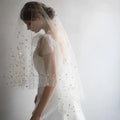 A golden shiny big veil made of white sheer fabric adorned with delicate star-shaped embellishments