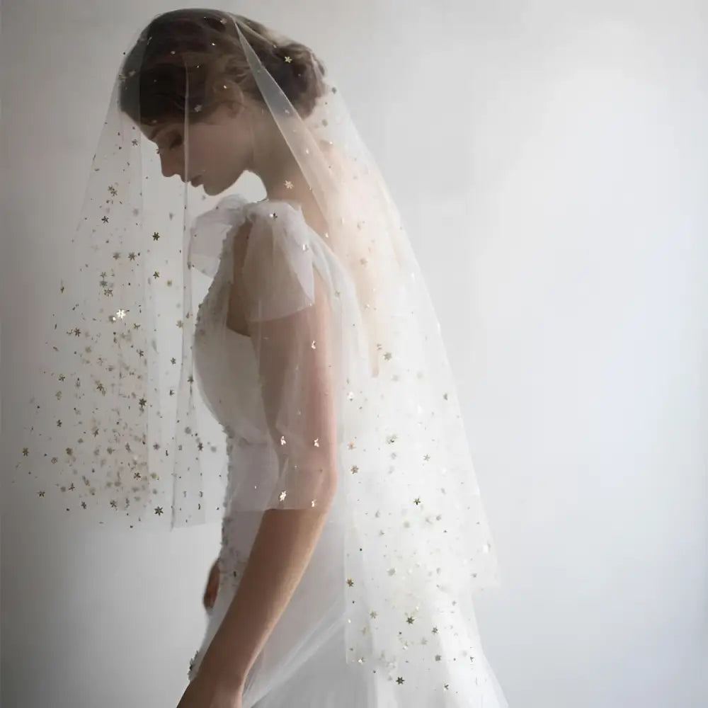 A golden shiny big veil made of white sheer fabric adorned with delicate star-shaped embellishments