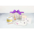 White embroidered eye mask with purple flower design included in grapefruit body scrub and wine glass spa gift basket