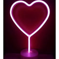 A glowing pink neon heart-shaped lamp with a cylindrical base offers perfect ambiance alongside green christmas tree led neon lights