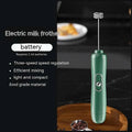 Green handheld battery version milk frother with a sleek ergonomic design and silver ornate whisk head in cylindrical body