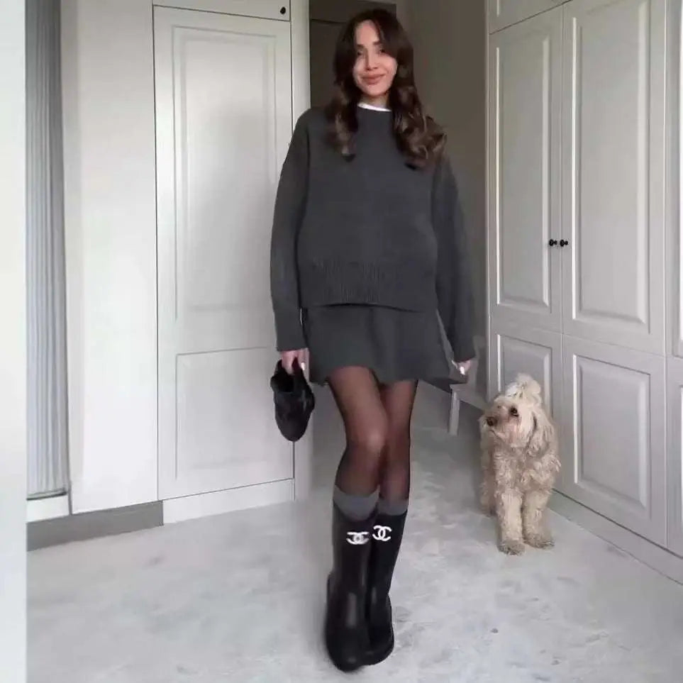 Black rubber boots with white chanel logo paired with green long sleeve knit casual sweater skirt sets