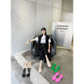 Black leather chair with sleek modern design and visible stitching displayed alongside green minimalist square toe block heel sandals