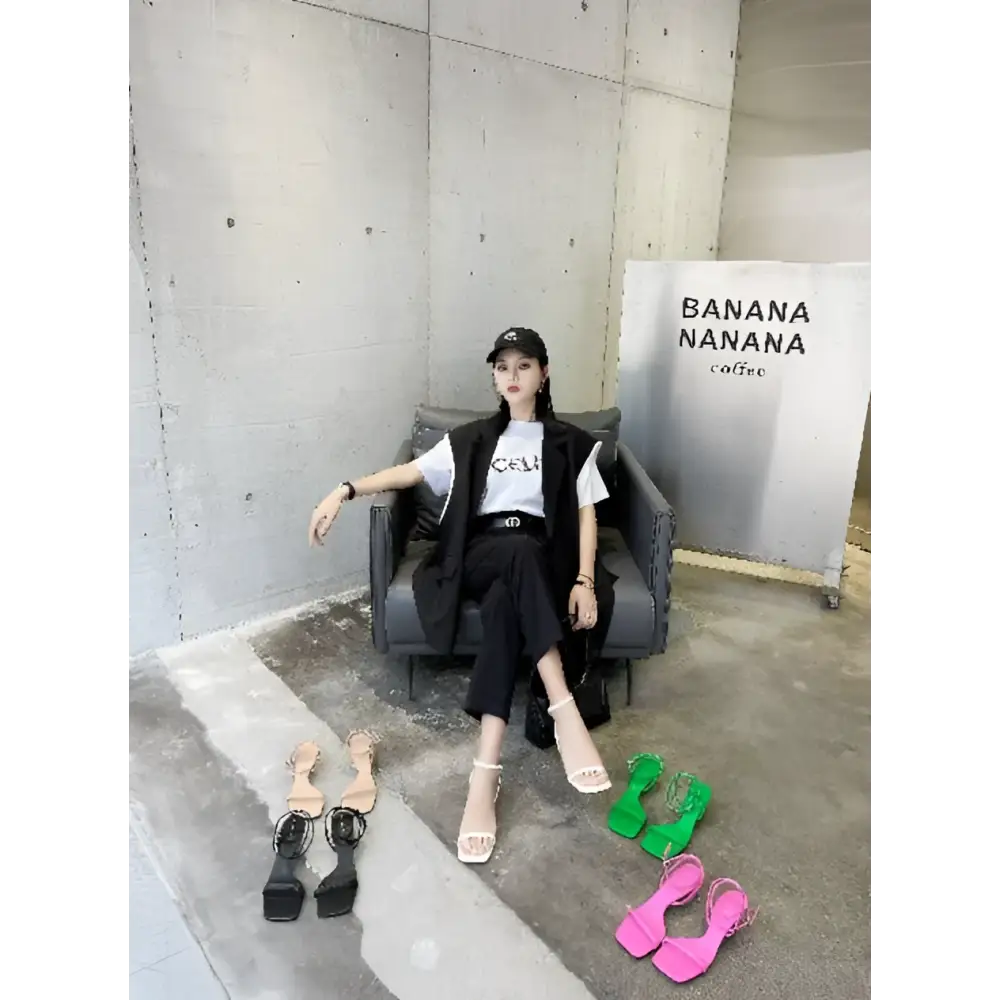 Black leather chair with sleek modern design and visible stitching displayed alongside green minimalist square toe block heel sandals