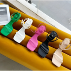 A row of five colorful minimalist square toe block heel sandals with thin straps and ankle ties in green white pink black and beige