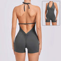 A sleek dark gray halter neck high yoga romper featuring a v-cut neckline with back tie and ruched detailing