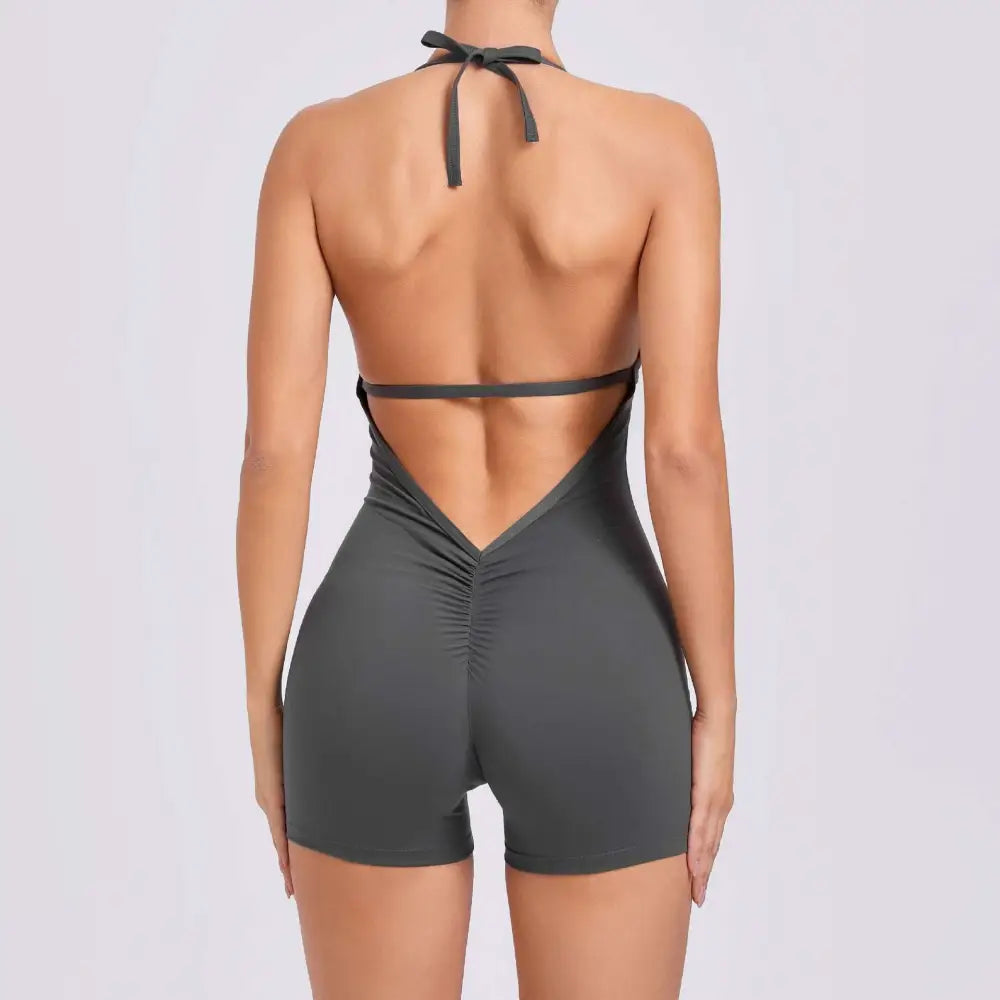 A sleek dark gray halter neck high yoga romper featuring ruched detailing and a back tie for a fitted look