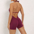 A maroon halter neck high elastic yoga romper featuring a v-cut neckline with ruched form-fitting shorts
