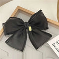 Elegant black handmade mesh bow hair clip made of sheer fabric with a small gold tag for women