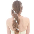 Handmade pearl white floral wedding hair chain woven with pearls and beads through a woman’s long brown braid