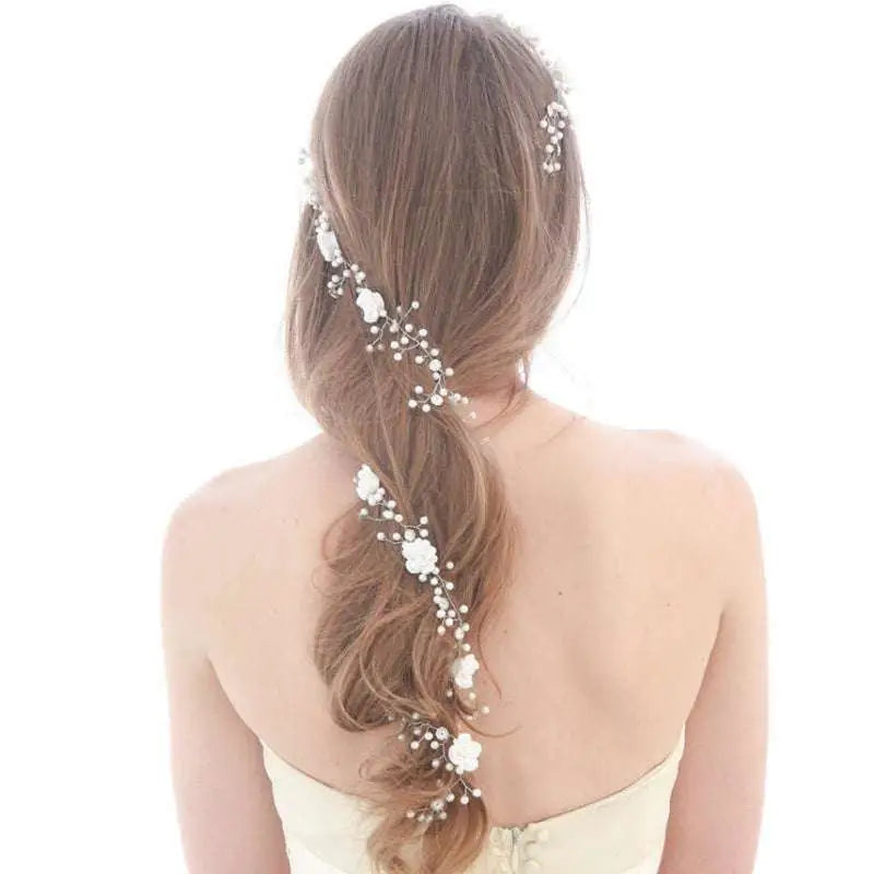Handmade pearl white floral wedding hair chain woven with pearls and beads through a woman’s long brown braid