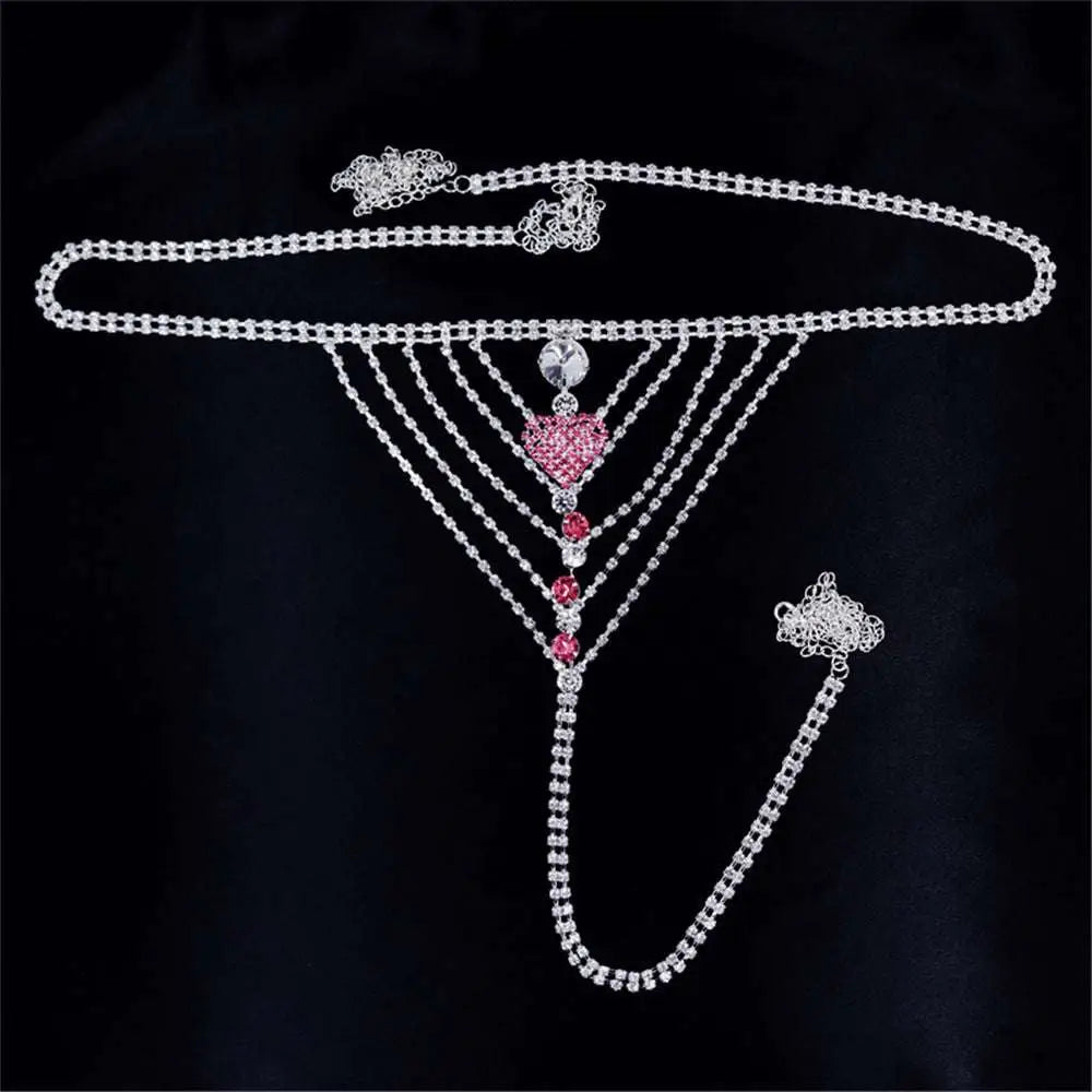 A silver rhinestone panty body jewelry with a central pink heart pendant and red gemstone garter belt accents