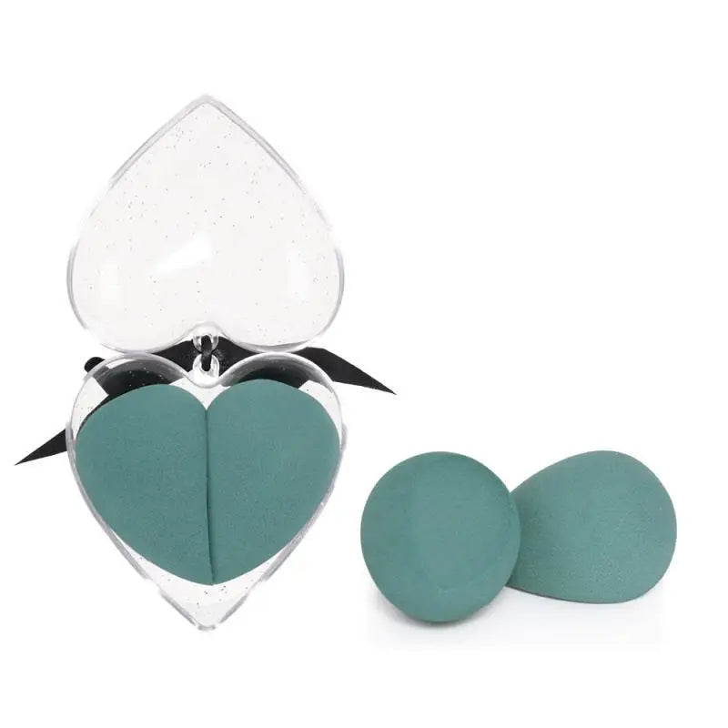 Heart shaped beauty egg makeup sponges in teal inside a clear glittery heart box with black ribbon gift packaging