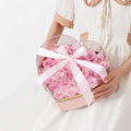 Heart shaped transparent flower packing box filled with soft pink preserved roses wrapped in white satin bow
