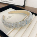 A sparkling silver heavy industry light luxury pearl style headband adorned with clear and blue-tinged rectangular crystals