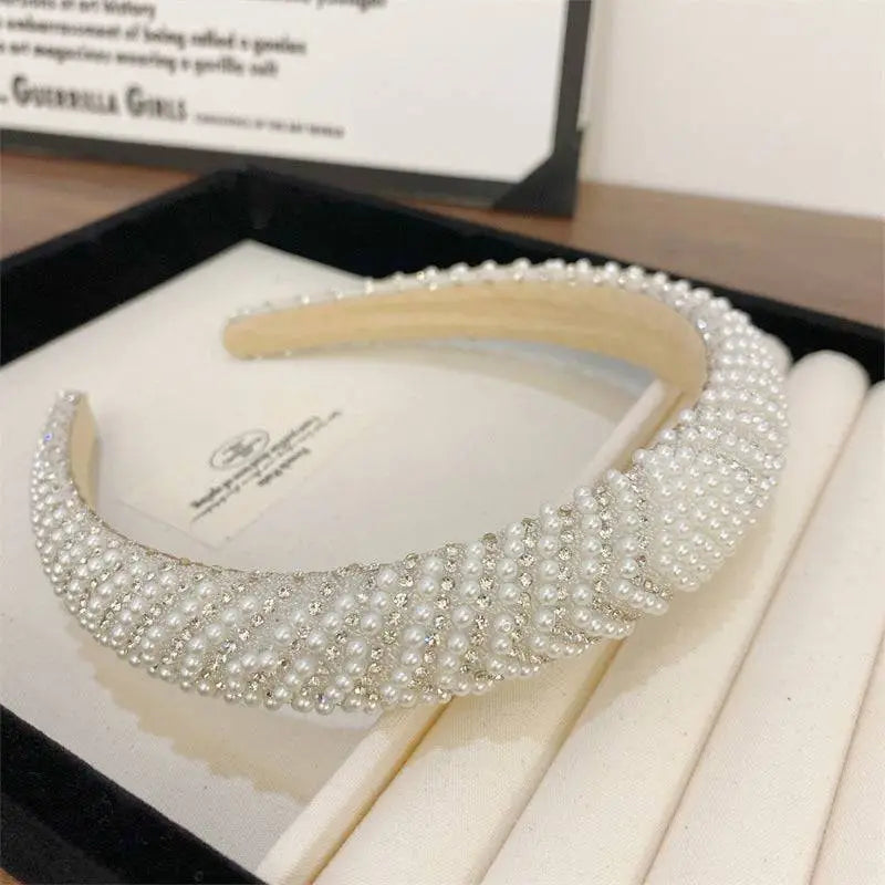 A heavy industry light luxury pearl style headband in white with sparkling silver crystals and a wide structured design