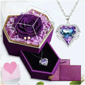 A sparkling heart pendant with purple blue crystal in silver set inside a hexagonal rose jewelry gift box with glass top