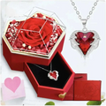 Hexagonal rose jewelry gift box with glass top displaying a sparkling red heart pendant with silver wings and crystals