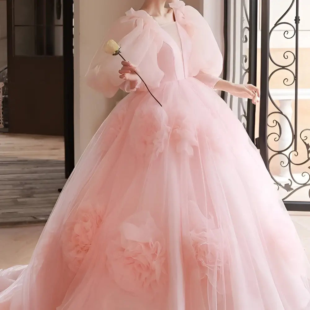 A blush pink tulle gown with voluminous puff sleeves and large floral appliqués for high end banquet style host